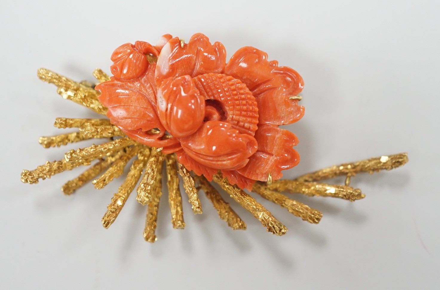 A 1970's? textured 14k yellow metal and carved coral mounted floral spray brooch, 62mm, gross weight 17.1 grams.